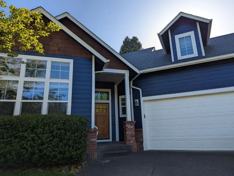 Navy lap siding with cedar-shingle accents and a white garage door