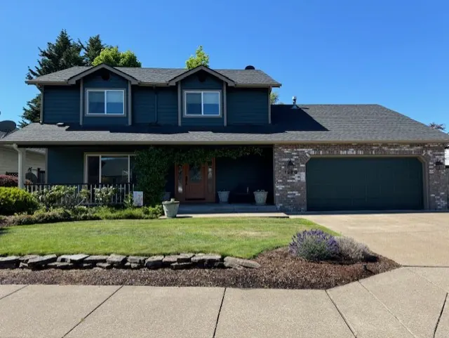 Two-story home with dark teal siding, brick and a matching garage door