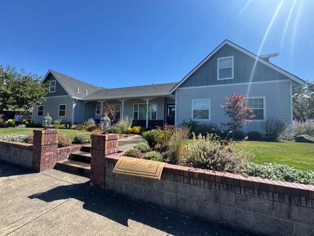 Gray-blue home with a covered porch and brick-framed landscaped entry
