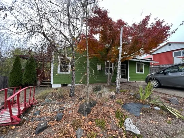 Small green house with white trim beside a red garden bridge